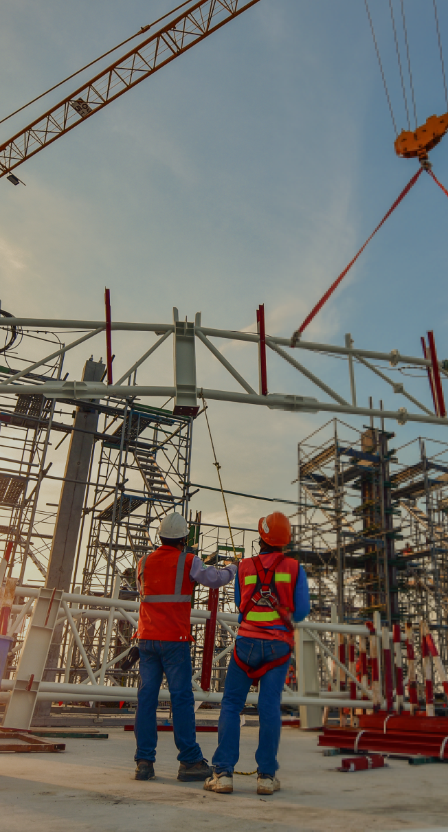 "Two engineers reviewing blueprints at a construction site